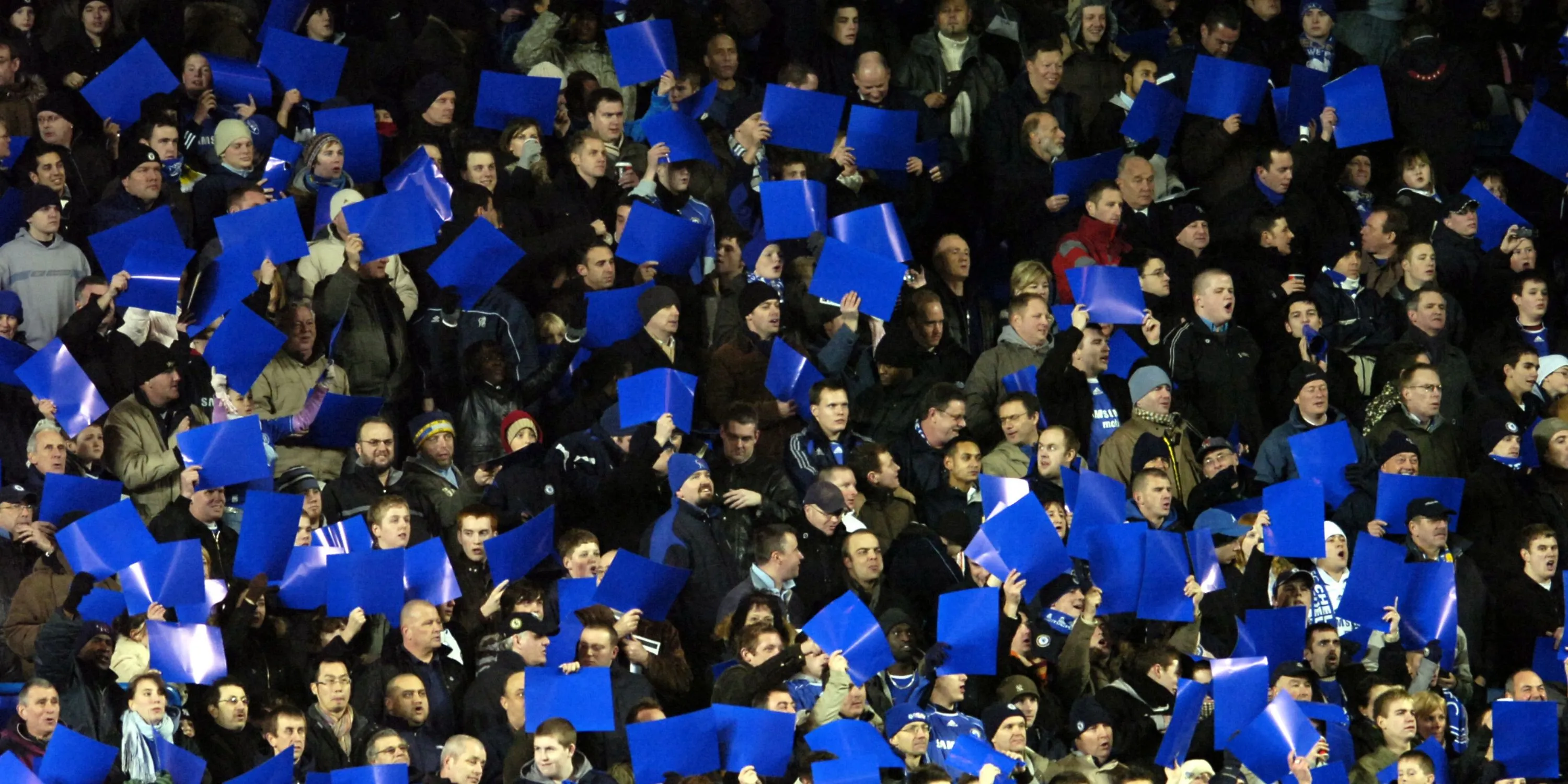 Người hâm mộ Chelsea cuồng nhiệt giơ cao biểu ngữ xanh, cổ vũ đội bóng tại Stamford Bridge.
